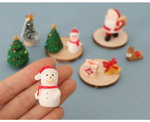 Macro shot of miniature resin snowman figurine and Christmas tree decorations on wooden base