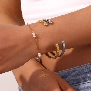 Gros plan de joncs ouverts dorés et argentés avec zircons et bracelet en perles