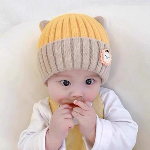 Detail of baby knit hat with 3D ears and cartoon lion patch in yellow and grey
