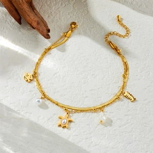 Zweilagiges goldenes Fußkettchen mit Seestern und Muschel auf weißem Hintergrund