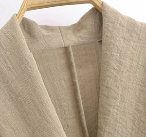 Close-up of oatmeal linen jacket lapel detail and precise stitching on wooden hanger