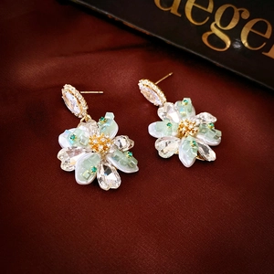 Detailed close-up of diamond-encrusted flower earrings on elegant dark silk fabric