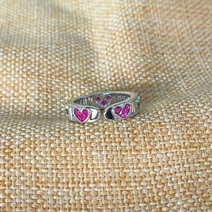 Detail of silver adjustable ring with pink heart stones and rectangular zircons