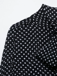 Detailed view of polka dot pattern on black chiffon fabric with soft shoulder seams