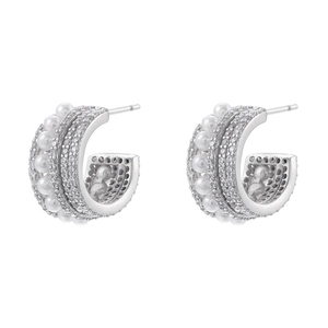 Macro detail of C-shaped silver earrings with micro-set zircons and elegant white pearls