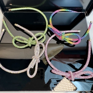 Detail of four sparkling rhinestone headbands featuring 3D bow designs in vibrant colors