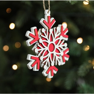 Detail of red and white wooden snowflake ornament hanging on a festive Christmas tree