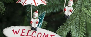 Close-up of metal snowman pendant and red striped umbrella ornament for Christmas tree