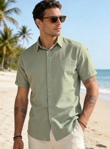 Close-up of sage green men's linen shirt with textured fabric and button details outdoors