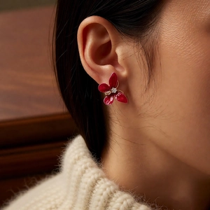 Détail de boucles d'oreilles fleur en émail rouge avec zircon porté par un mannequin