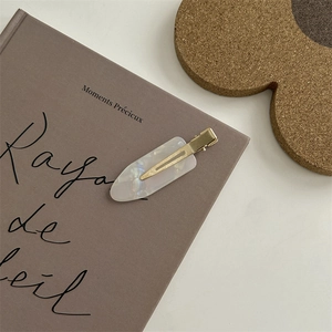 Dettaglio dell'elegante fermaglio per capelli bianco perlato su un libro vintage