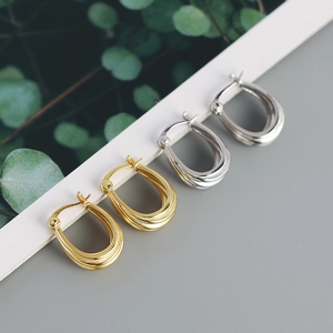 Detail of minimalist S925 silver U-shaped geometric spiral hoop earrings in gold and silver