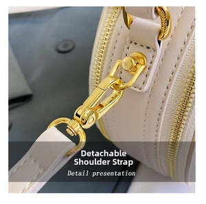 Detailed close-up of the golden metal buckle and strap on a beige round crossbody bag