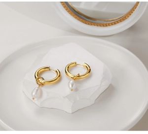 Detail of gold-plated stainless steel hoop earrings with natural baroque pearl pendants
