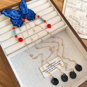 Détail d'une pince à cheveux papillon brodée bleue avec gland doré et perles