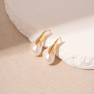 Boucles d'oreilles perles baroques avec métal doré sur une surface en pierre