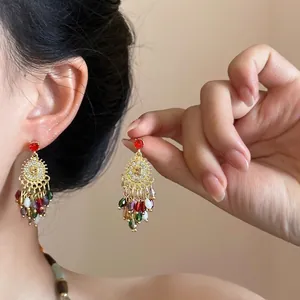 Détail macro de boucles d'oreilles bohèmes avec perles colorées et texture dorée sur modèle