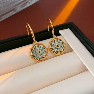 Close-up of vintage flower earrings with colorful enamel and green zircon in a gift box