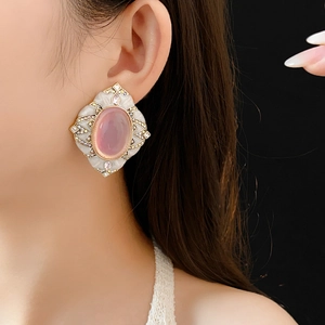 Close-up of vintage-style oval pink gemstone earring with white enamel and crystals