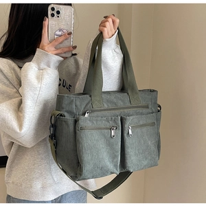 Green corduroy tote bag with multiple zip pockets shown in a mirror selfie for size scale