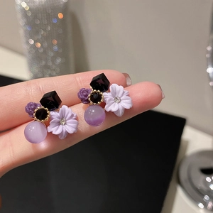 Close-up of purple flower earrings with geometric black stone and cat eye bead details