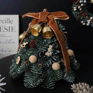 Mini Christmas tree with green needles, velvet bow, and golden bells for desktop decor