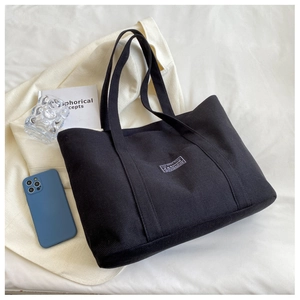 Detailed close-up of large black canvas tote bag showing the fashion woven label and texture