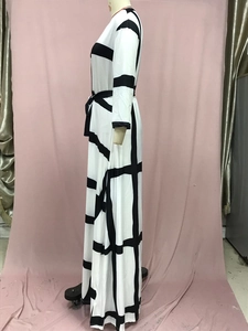 Detail of a black and white checkered long dress featuring long sleeves and a belted waist
