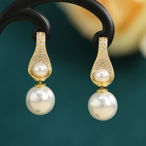 Detailed view of teardrop gold earrings with white pearls and micro-paved cubic zirconia