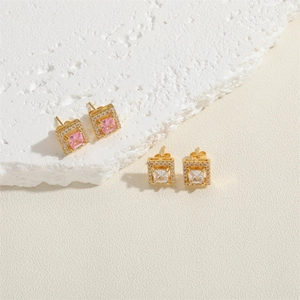 Detailed view of square zircon stud earrings in pink and white on a marble display stone