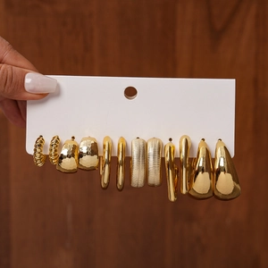 Detailed view of 12-piece gold geometric earring set held against wood background