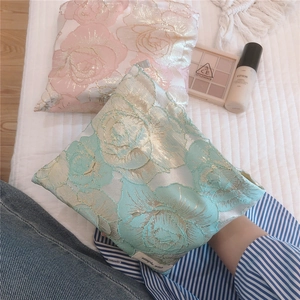 Detail of rose gold jacquard makeup bags in pink and mint green on quilted fabric