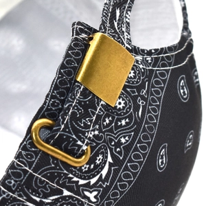 Detail view of a black paisley baseball cap featuring a brass metal adjustment buckle