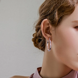 Detail view of 925 sterling silver twisted hoop earrings on model in minimalist style