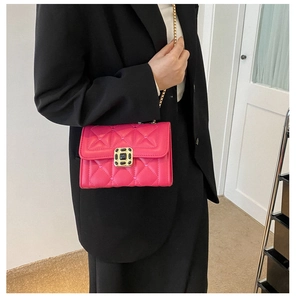Close-up of pink quilted crossbody bag with golden chain and black gemstone buckle