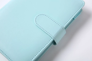Close-up of mint blue leather notebook cover showing stitching and buckle texture
