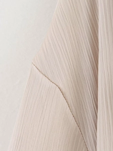 Gros plan sur la texture du tissu plissé beige et les coutures de la veste de costume