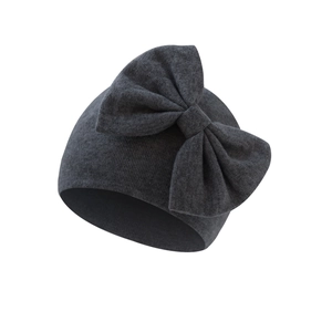 Detailed view of dark grey knitted baby beanie with a large decorative bow tie