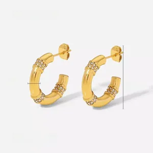Détail de boucles d'oreilles créoles dorées style bambou avec zircons blancs, 2,3 cm