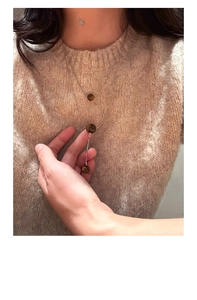 Details einer silbernen Doppelkette mit braunen Tigerauge-Perlen auf beigem Pullover
