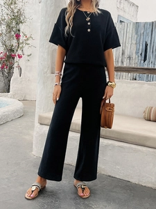 Detail of black knitted two-piece set featuring textured short sleeves and wide-leg trousers