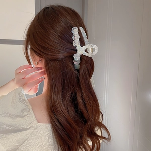 Gros plan sur la pince à cheveux nacrée irisée élégante avec un design à bords ondulés