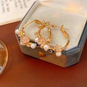 Detailed close-up of vintage hoop earrings with pink enamel flowers and pearls