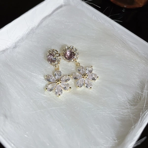 Macro shot of a floral earring with purple cubic zirconia and clear stones on white velvet