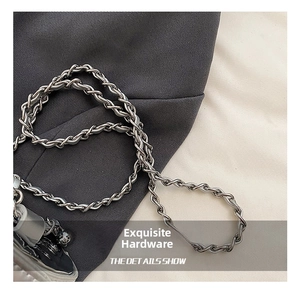Detailed close-up of polished silver woven metal chain strap on a stylish crossbody bag