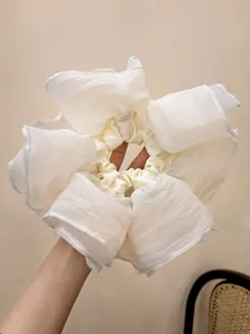 Detail view of large white pleated mesh hair scrunchie with layered organza texture