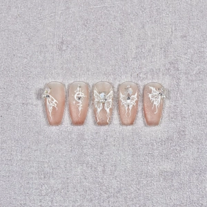 Detailed view of handmade gradient nude coffin nails with butterfly patterns and pearls