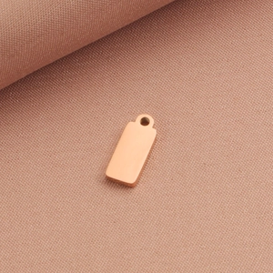 Macro shot of blank rose gold rectangular metal pendant with smooth polished finish