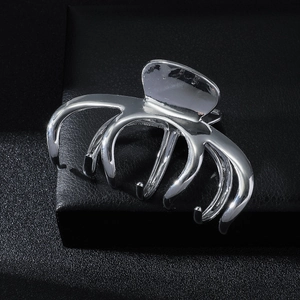 Sleek silver metal hair claw clip with multi-claw design on premium black leather backdrop