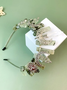 Detail of silver crown headband featuring green raw stones, crescent moon and sun accents